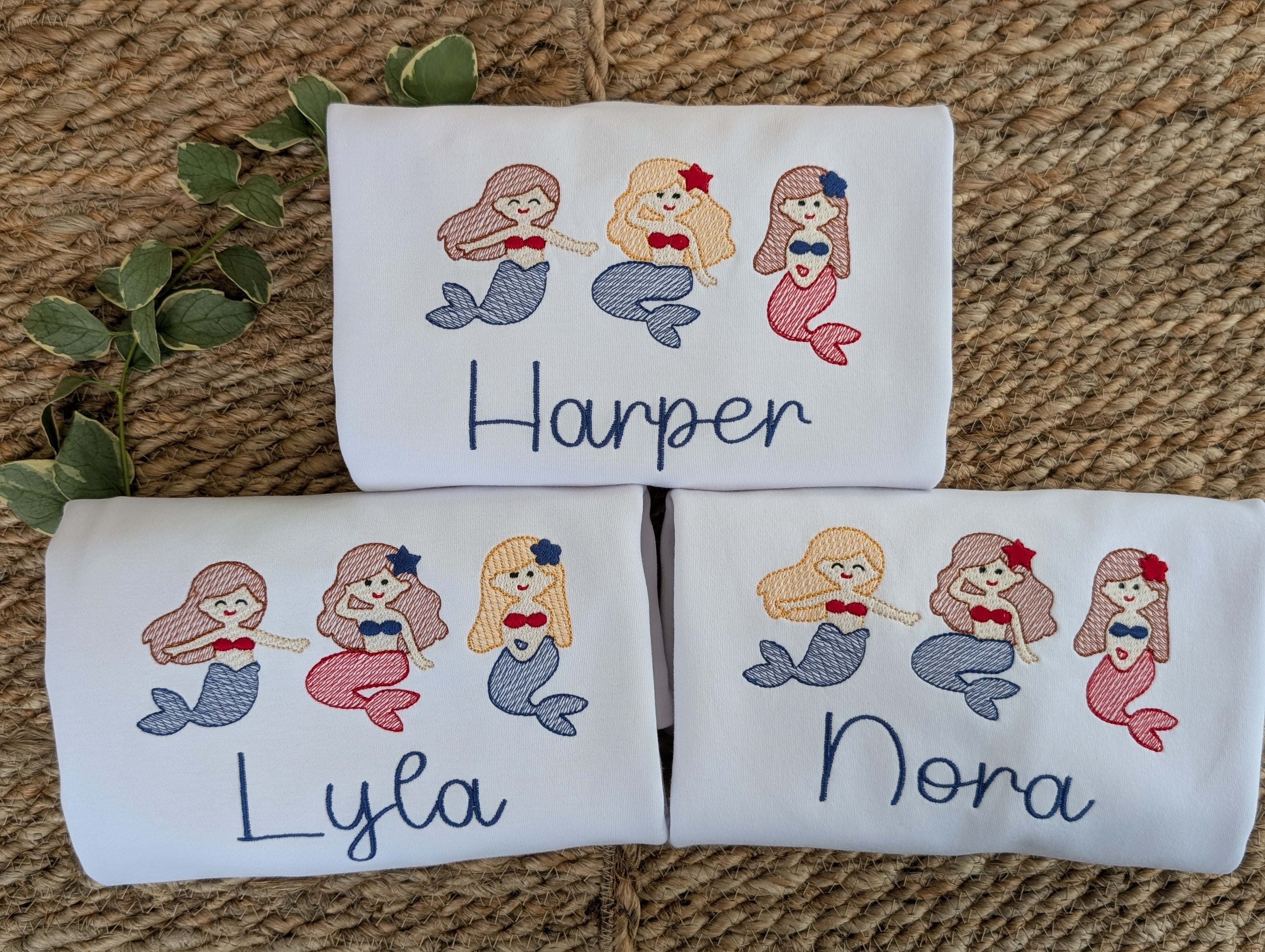 White tees with embroidered mermaid trio design personalized with names Harper, Lyla, and Nora