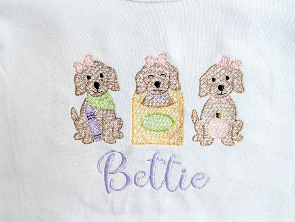 Close-up of puppy trio embroidery detail on onesie with name Bettie