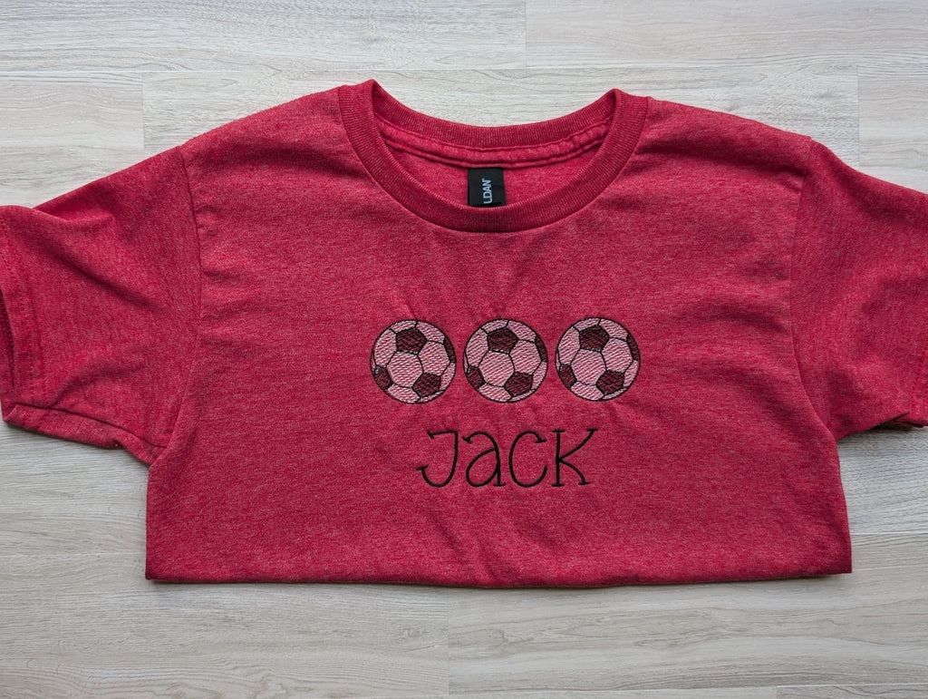 Heathered red kids tee with personalized soccer ball trio embroidery, name Jack, flat lay