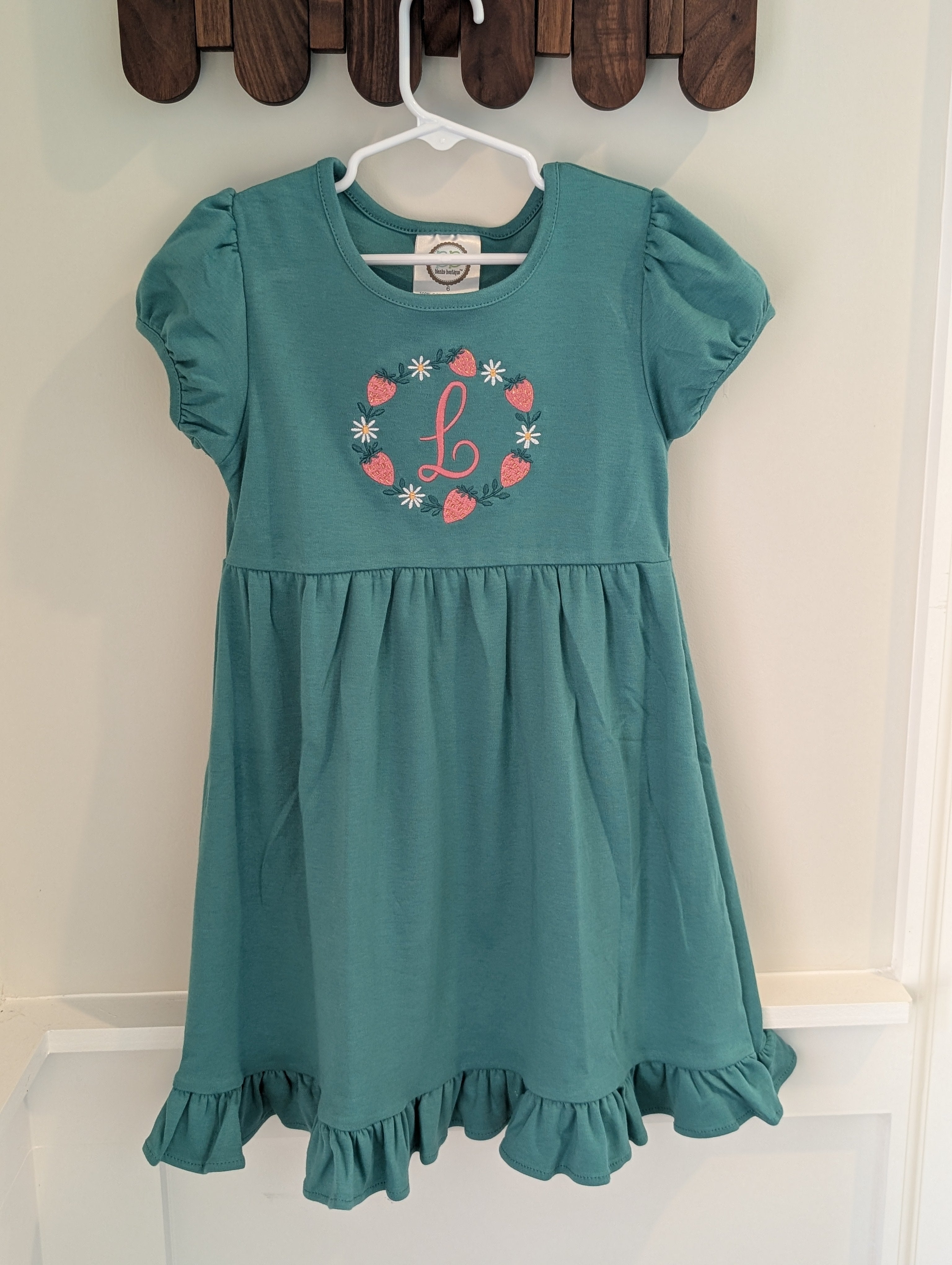 Strawberry monogram embroidered girls dress, folded flat lay