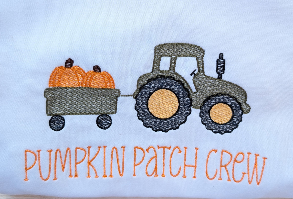 Close-up of embroidered tractor with pumpkin wagon and Pumpkin Patch Crew text on white tee