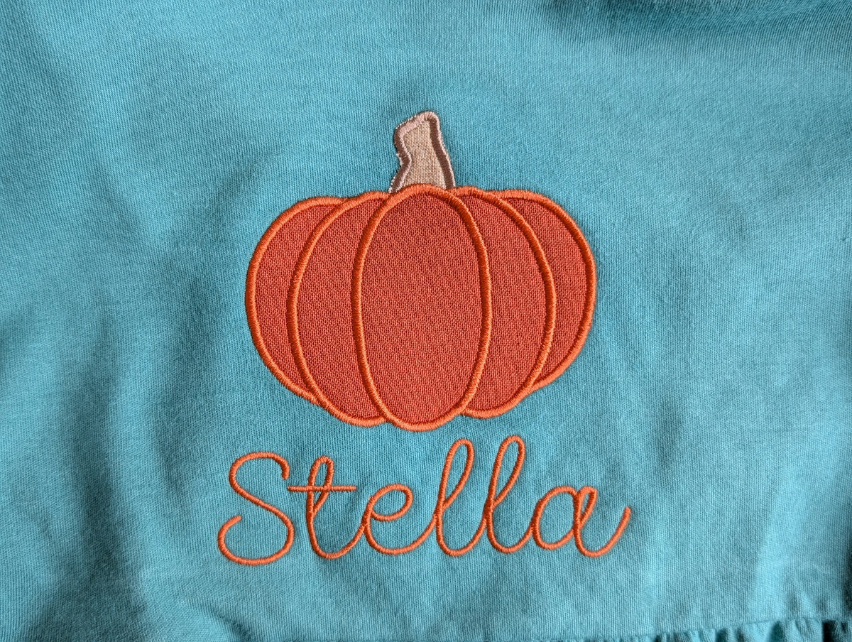 Teal ruffle top with pumpkin applique and name embroidery - flat lay
