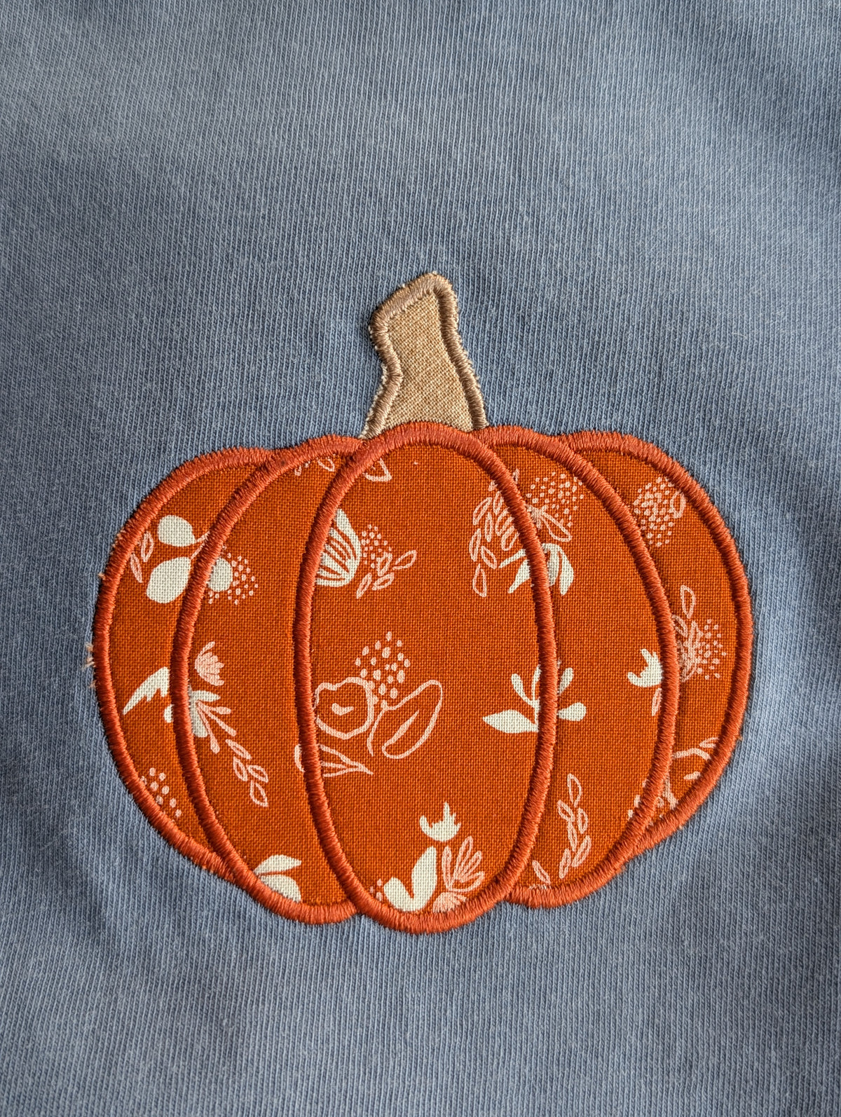 Close-up of fabric pumpkin appliqué on denim Comfort Colors tee