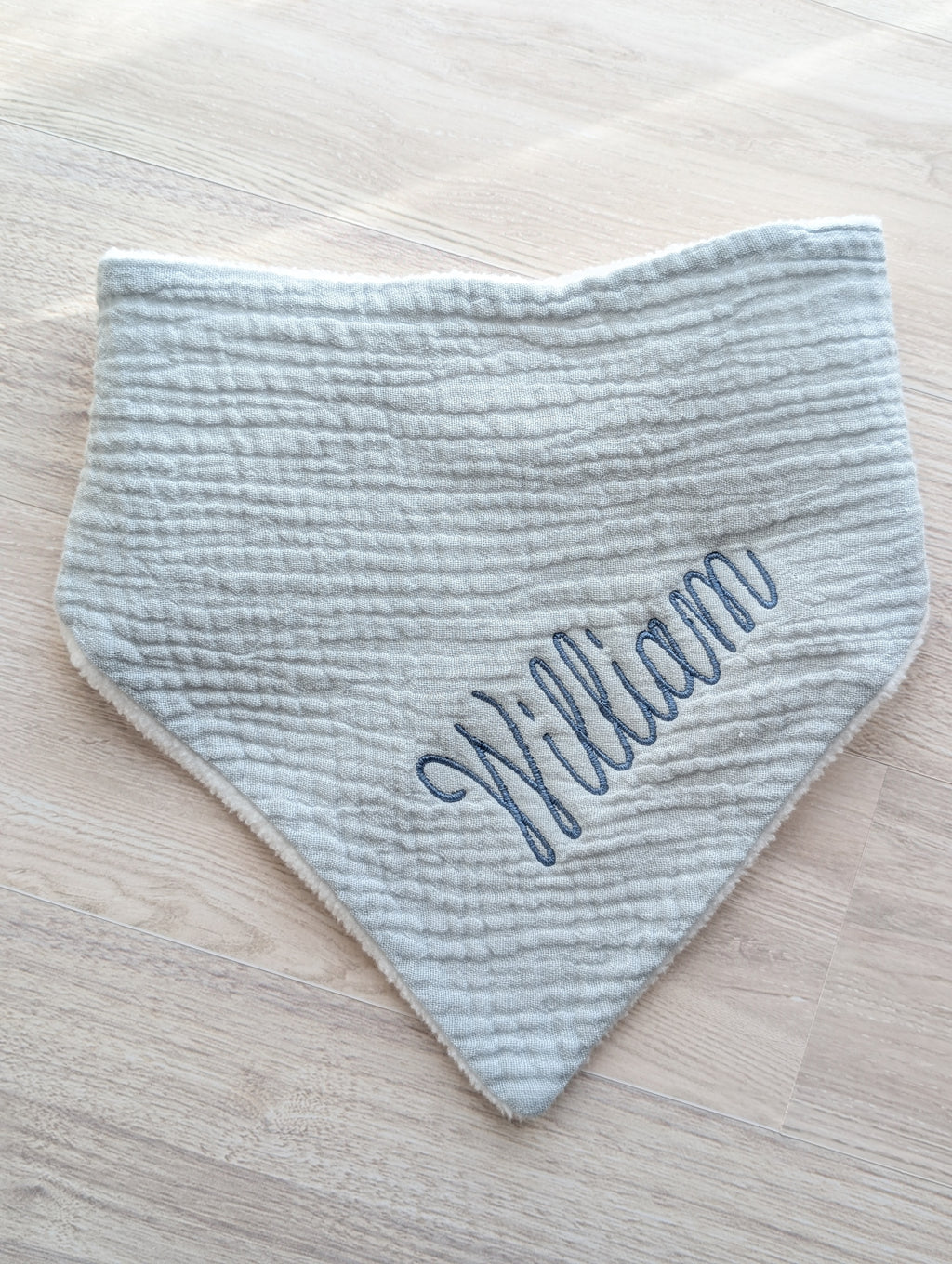 Gray baby bib embroidered with a personalized name