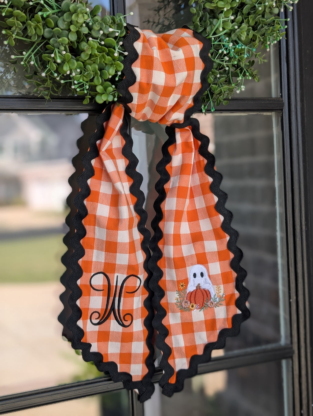 Orange gingham ghost and pumpkin wreath sash with black ric rac trim on a green wreath