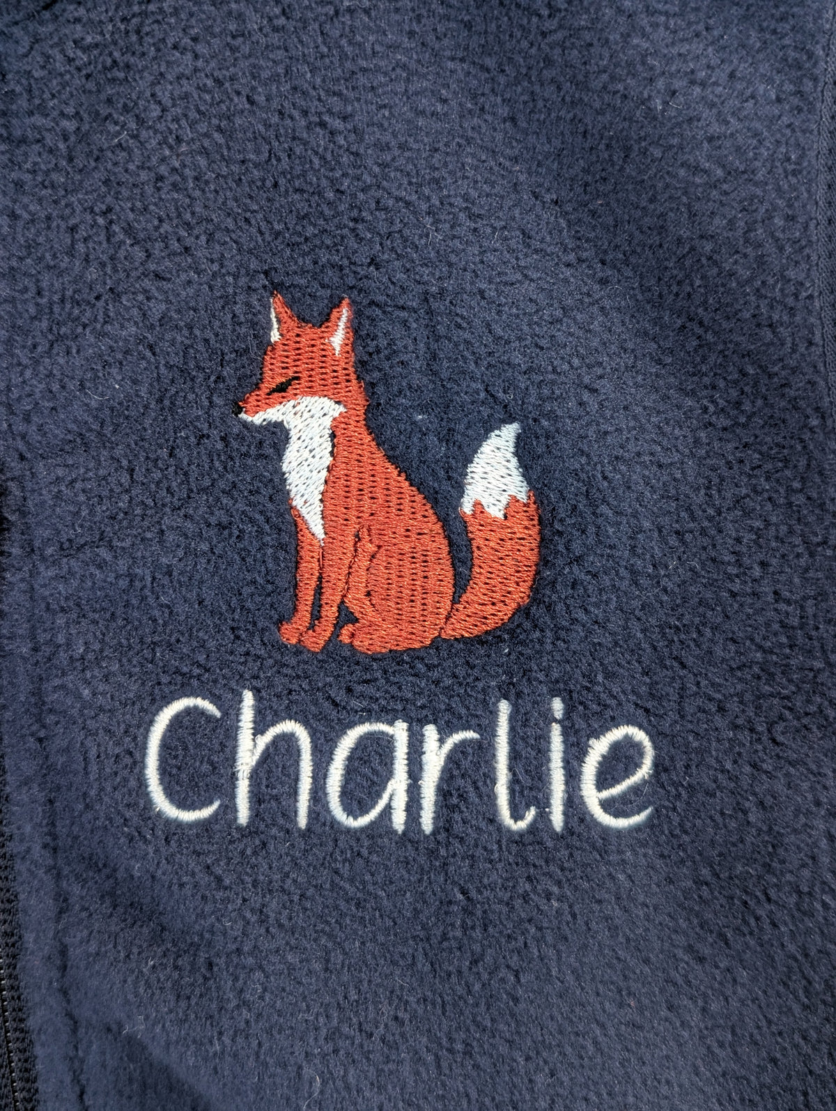 Close-up of fox embroidery and Charlie name on navy fleece