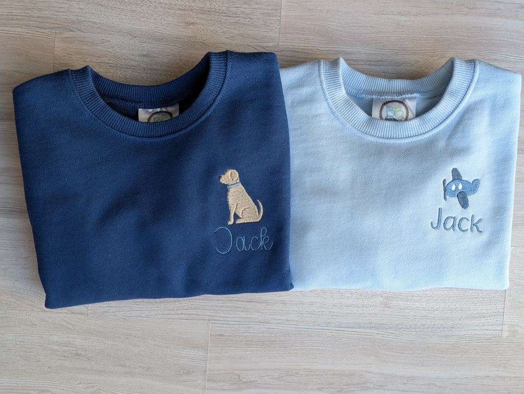 Close-up of airplane embroidery and Jack name on light blue sweatshirt